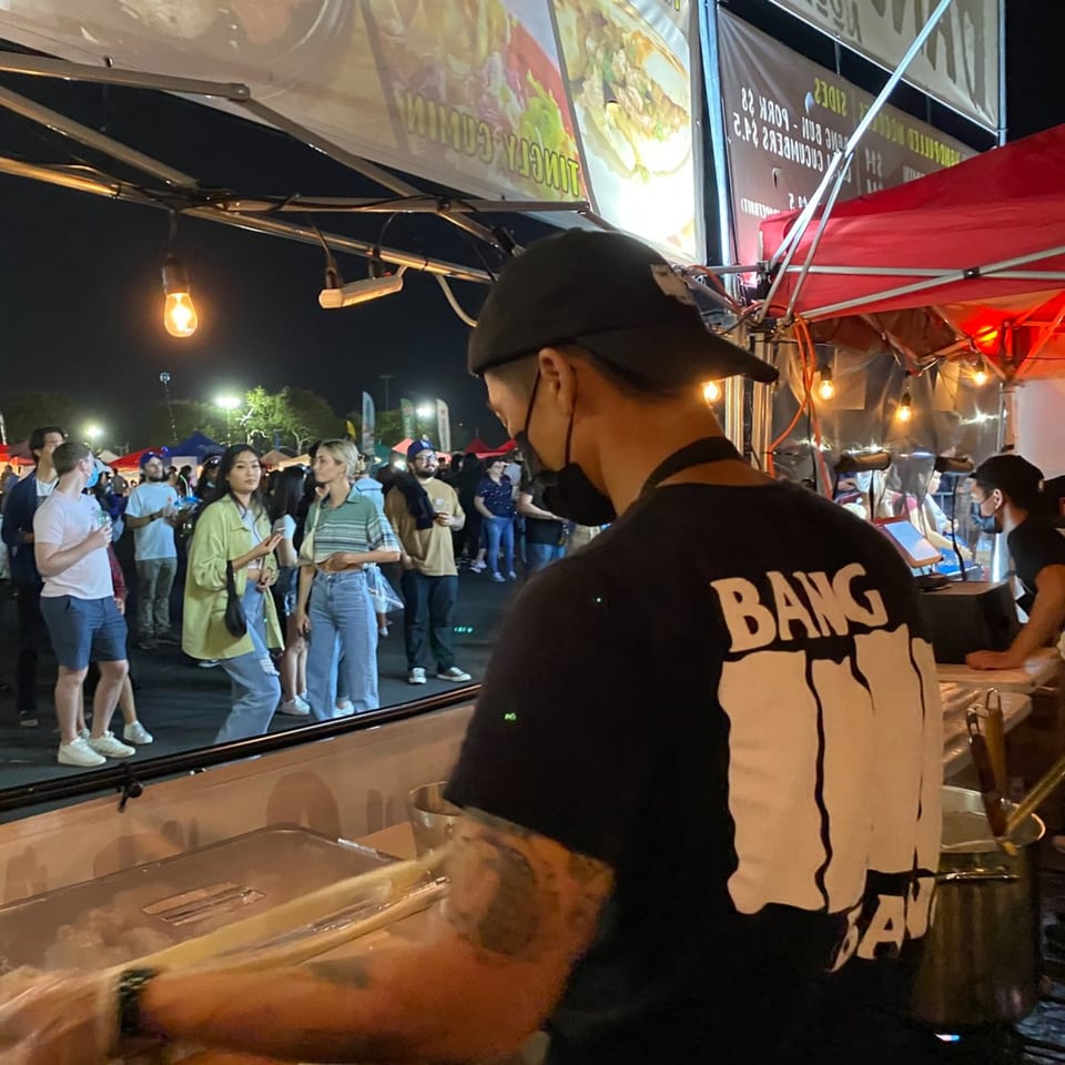 A Bang Bang Noodles chef prepares food at a bustling night market stall.